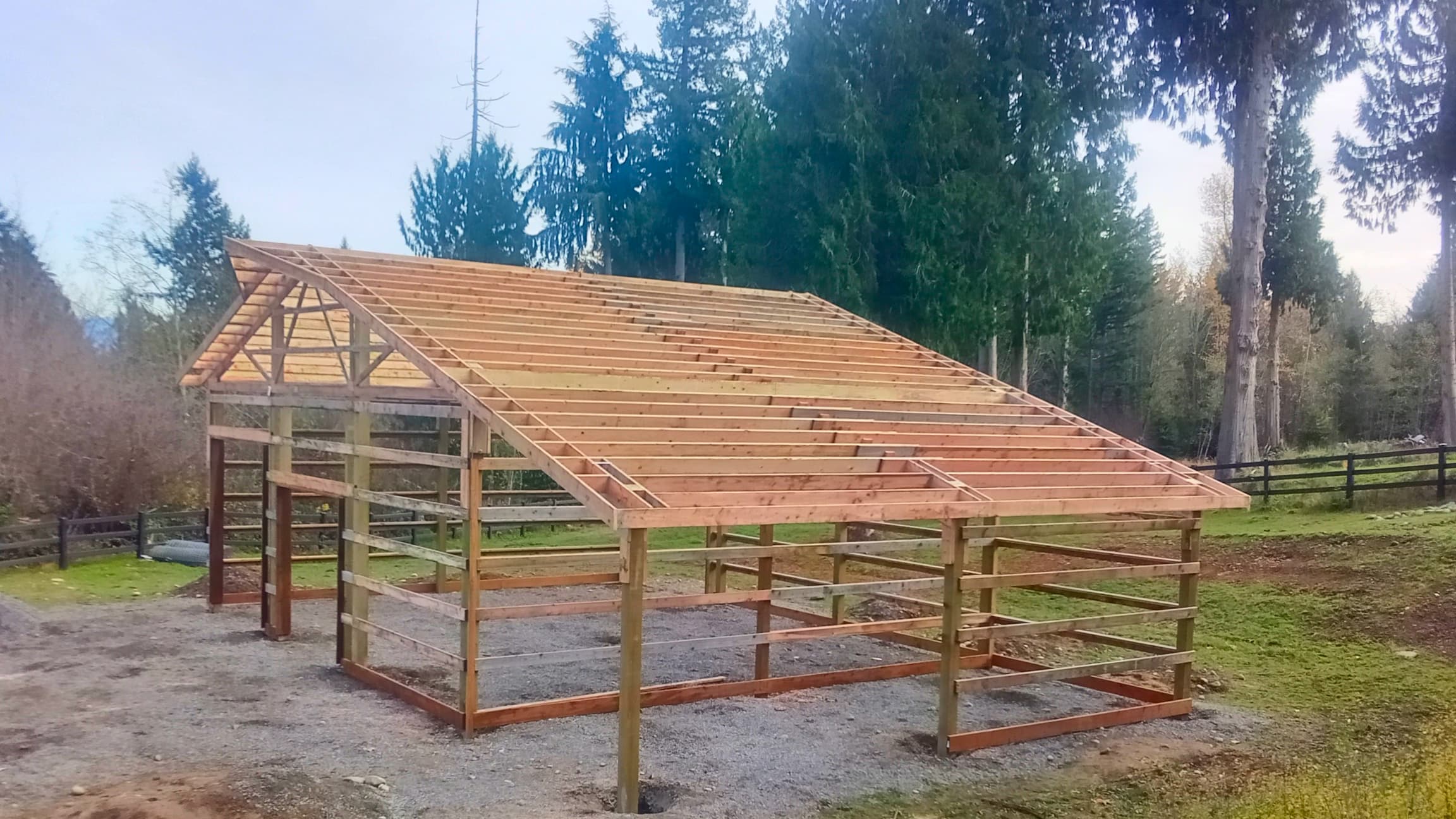 Early construction phase of a 36'x36' pole building showing the post-frame structure and roof trusses. This Probuilt Metal Buildings project in Lake Tapps demonstrates the solid foundation and quality framing that supports the finished steel building, with gravel base preparation for proper drainage.