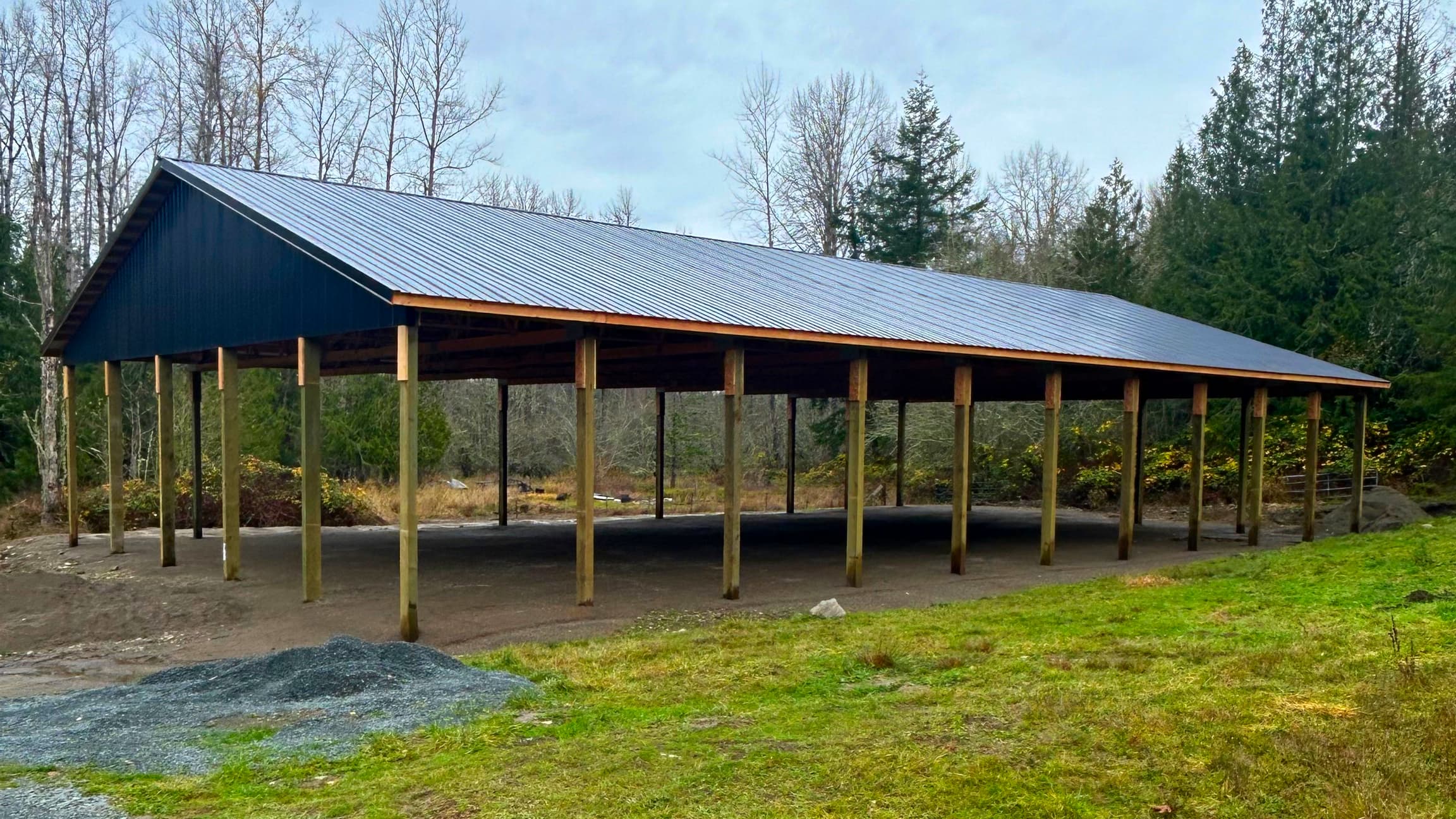 Angled view of our premium 60x100 equestrian arena in Eatonville, WA. This 16-foot tall metal structure with durable black roofing offers ideal coverage for training and riding. Custom designed and built by Probuilt Metal Buildings for Pacific Northwest horse owners.
