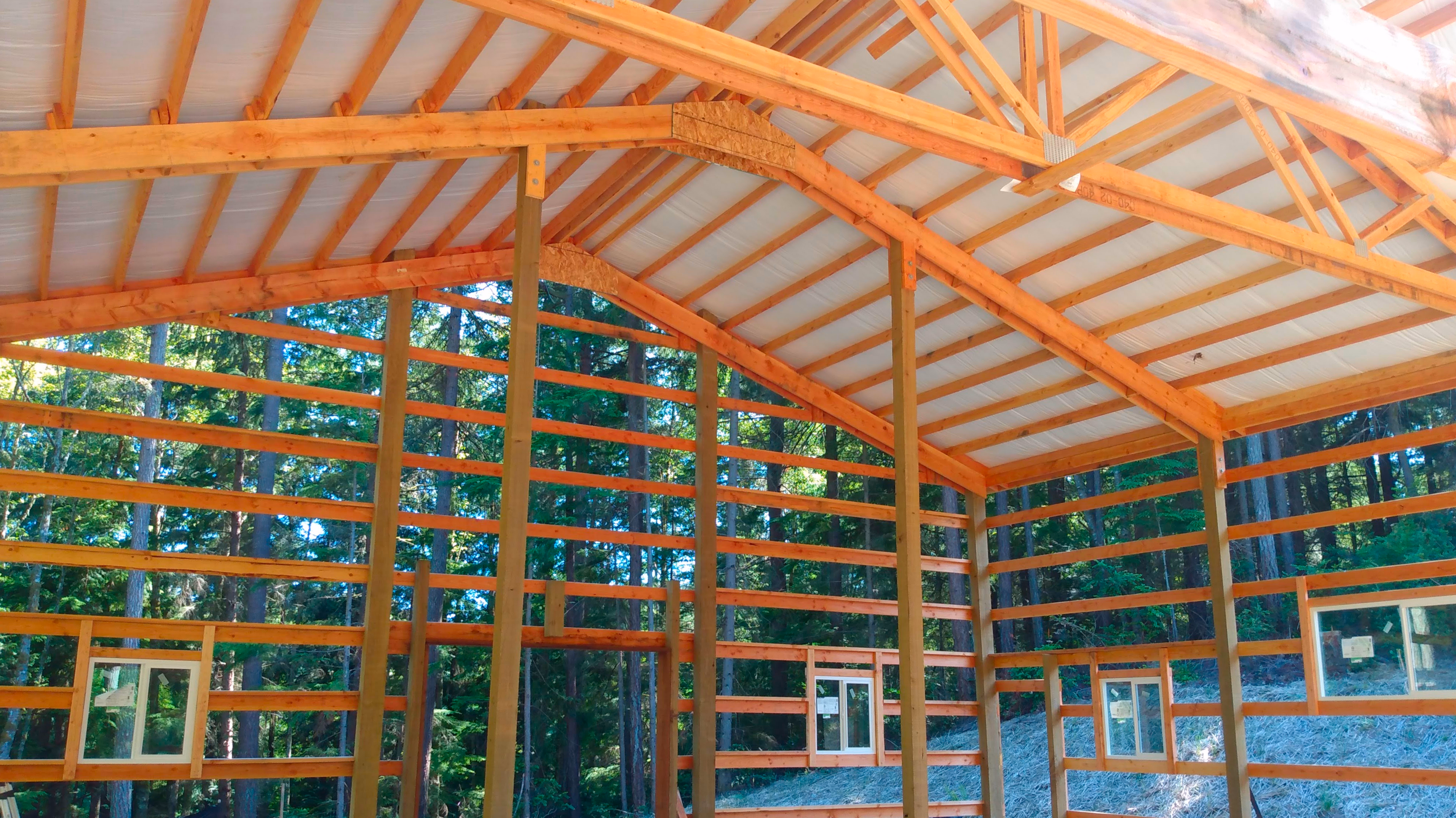 Interior view of a 36'x36' Probuilt Metal building in Olalla showing completed roof installation with insulation. This 16' tall structure features engineered trusses and extensive wood framing for superior durability in Pacific Northwest conditions.