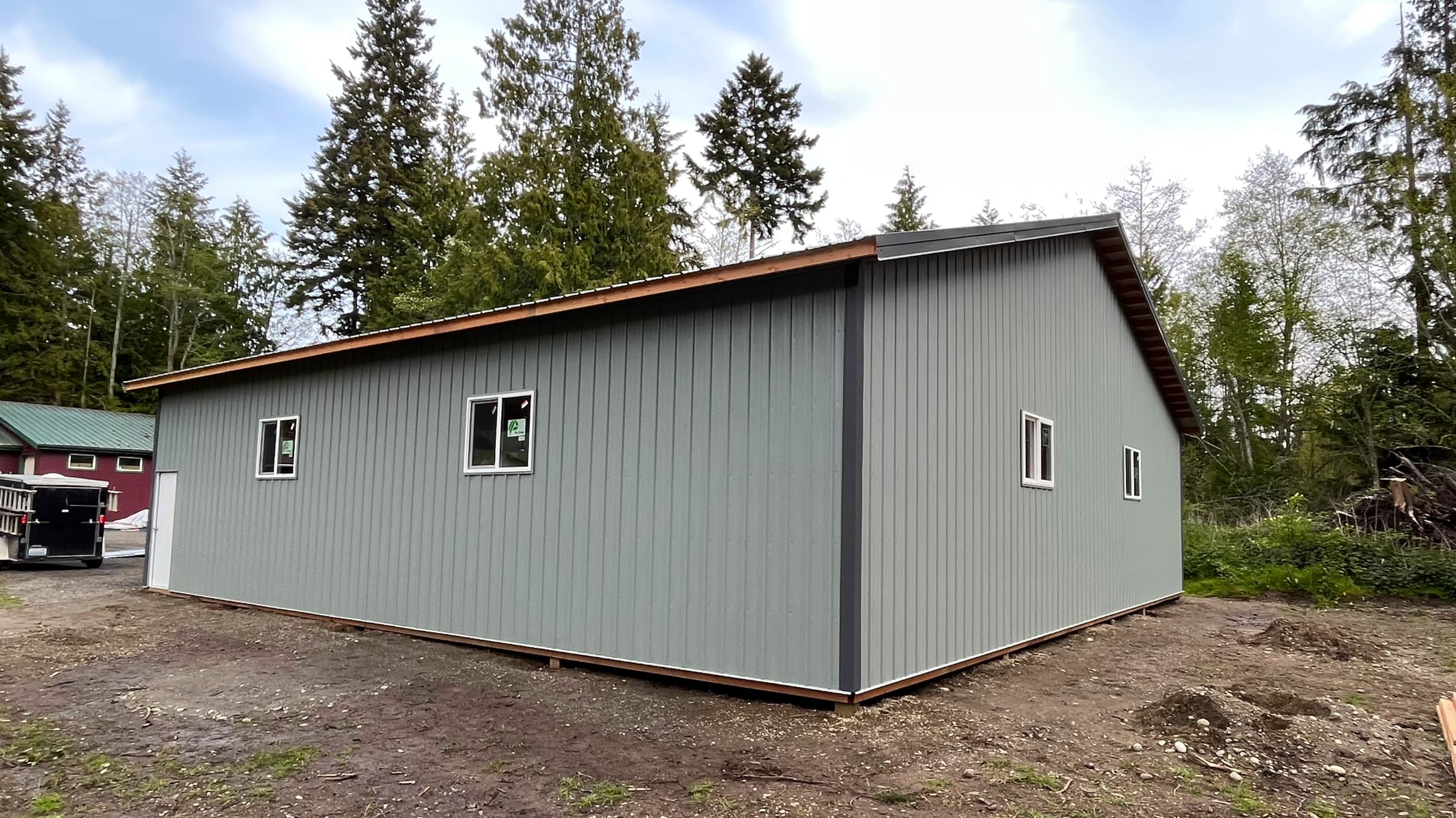 Full exterior view of completed 40'x48' Probuilt metal building featuring walk-in door access and premium ash grey siding. This Port Orchard structure demonstrates the perfect balance of functionality and aesthetic appeal with 18-inch overhangs and expert finishing touches. Ideal for commercial, workshop, or storage applications in the Pacific Northwest.