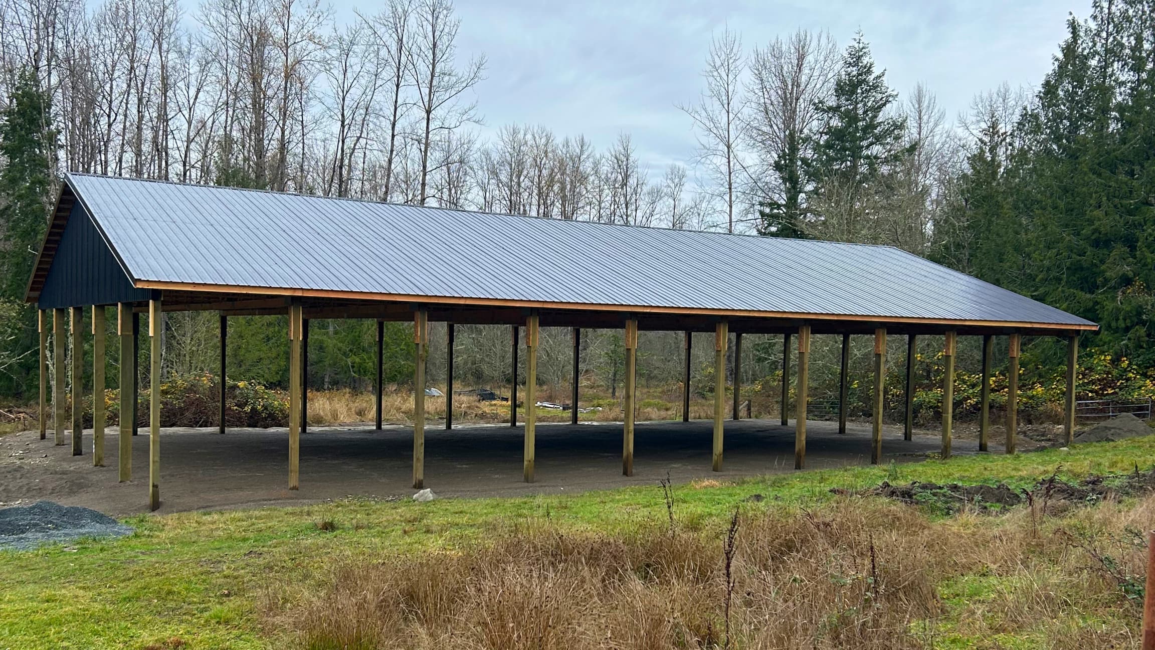 Side profile of a spacious 60x100 covered horse arena by Probuilt Metal Buildings. The open-sided design with black roof provides weather protection while maintaining excellent ventilation and natural light for equestrian activities in Eatonville, WA.